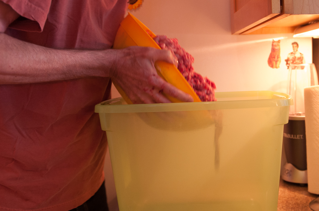 pouring ground meat into large container